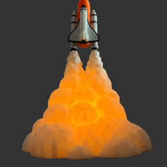 A space shuttle model launching from an illuminated glowing cloud base, set against a plain gray wall and dark wooden surface.