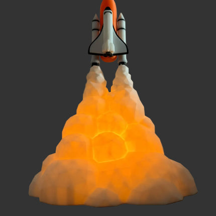 A space shuttle model launching from an illuminated glowing cloud base, set against a plain gray wall and dark wooden surface.